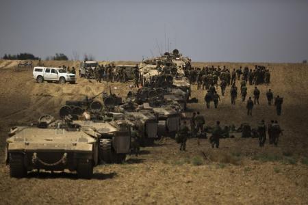 En la imagen, soldados israelíes caminan junto a sus tanques tras regresar a Israel desde la Franja de Gaza