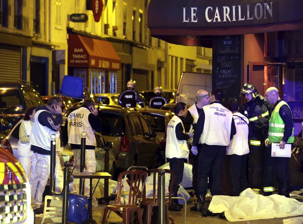 A general view of the scene shows rescue service personnel working near the covered bodies outside a restaurant following a shooting incident in Paris